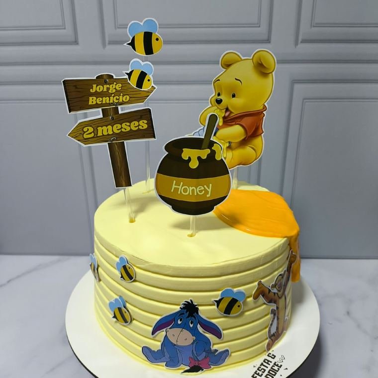 Bolo amarelo decorado no tema Ursinho Pooh para mesversário.