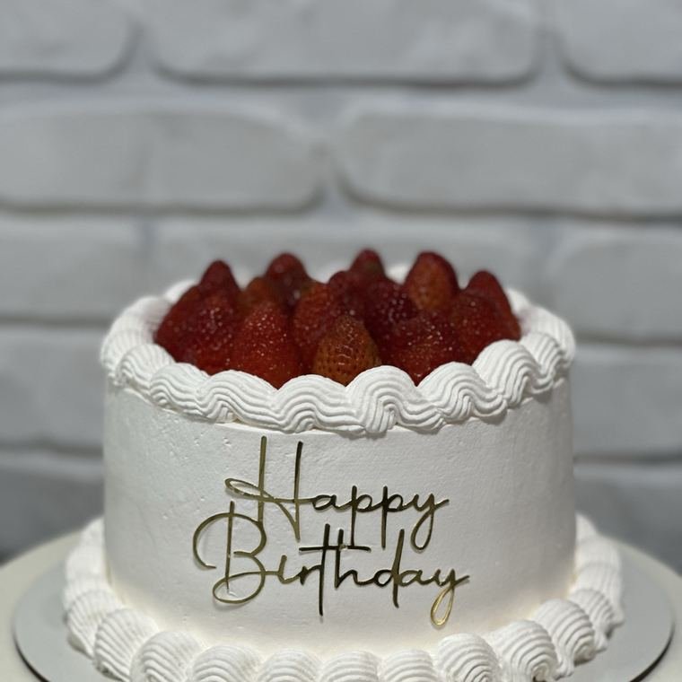 Bolo branco com morangos e topo Happy Birthday.